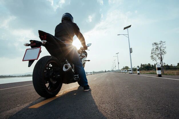 motorcyclist wearing the proper safety gear and helmet riding on a road